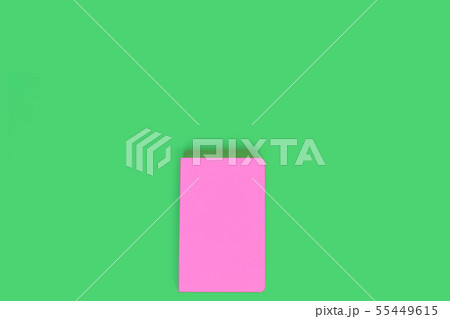 Pink closed notebook on light green background Pink closed notebook on light green background 55449615