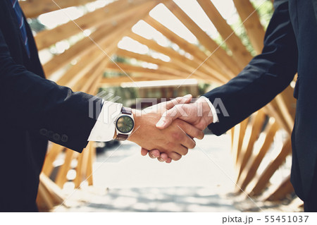 Close up of two men shaking hands while standing outdoors 55451037