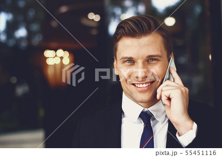 Portrait of handsome smiling man talking on the phone outdoors 55451116