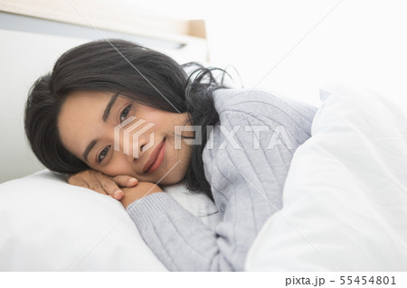 Asian woman lies on one side on bed in bedroom.. Asian woman lies on one side on bed in bedroom.. 55454801