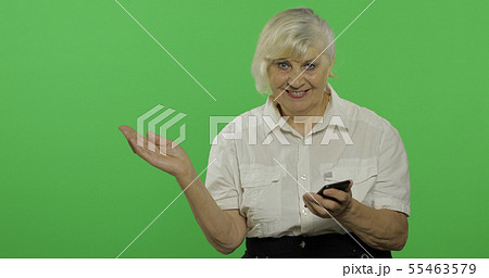 An elderly woman adjusts her clothes and smiles. Chroma key 55463579
