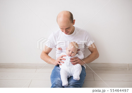Children, family and fatherhood concept - happy bald father holding baby daughter on knees on white Children, family and fatherhood concept - happy bald father holding baby daughter on knees on white 55464497