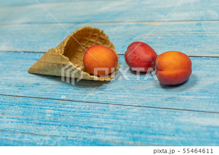 Fruit season. Fruit ice cream. Apricot in a waffle on a blue wooden background Fruit season. Fruit ice cream. Apricot in a waffle on a blue wooden background 55464611