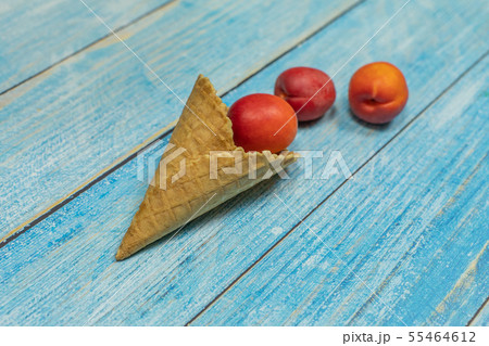 Fruit season. Fruit ice cream. Apricot in a waffle on a blue wooden background Fruit season. Fruit ice cream. Apricot in a waffle on a blue wooden background 55464612