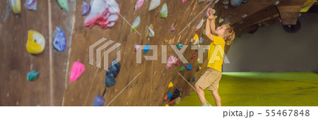 little boy climbing a rock wall in special boots. indoor BANNER, LONG FORMAT 55467848