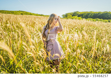Young beautiful woman in autumn landscape with dry flowers, wheat spikes. Fashion autumn, winter Young beautiful woman in autumn landscape with dry flowers, wheat spikes. Fashion autumn, winter 55468257