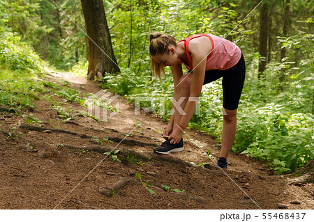 woman stopped jogging in a mountain forest to tie 55468437