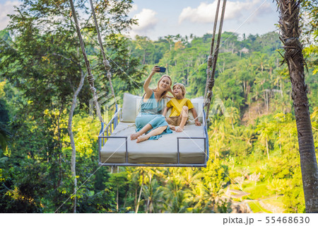 Mother and son swinging in the jungle rainforest of Bali island, Indonesia. Swing in the tropics 55468630