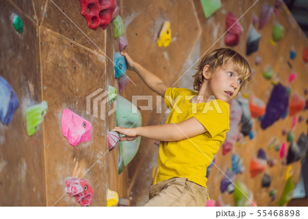 little boy climbing a rock wall in special boots. indoor 55468898