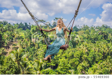 Young woman swinging in the jungle rainforest of Bali island, Indonesia. Swing in the tropics 55469360
