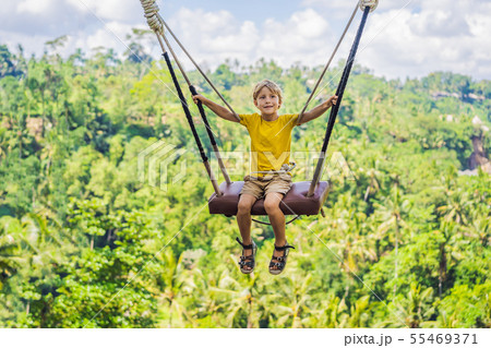 Young boy swinging in the jungle rainforest of Bali island, Indonesia. Swing in the tropics. Swings 55469371