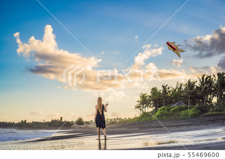 A young woman launches a kite on the beach. Dream, aspirations, future plans 55469600
