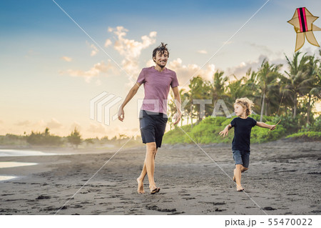 Young father and his son running with kite on the beach Young father and his son running with kite on the beach 55470022