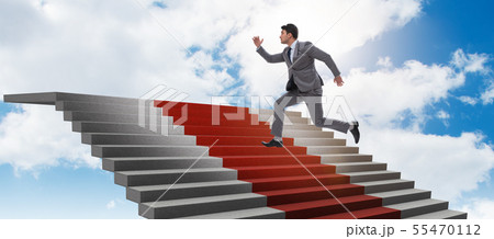 Young businessman climbing stairs and red carpet into sky 55470112