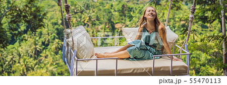 Young woman swinging in the jungle rainforest of Bali island, Indonesia. Swing in the tropics Young woman swinging in the jungle rainforest of Bali island, Indonesia. Swing in the tropics 55470113