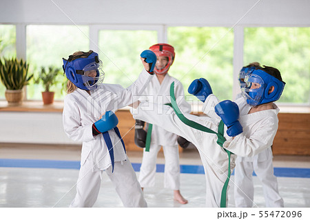 Boy and girl wearing helmets and boxing gloves having a fight Boy and girl wearing helmets and boxing gloves having a fight 55472096