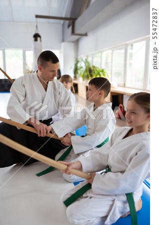 Dark-haired aikido trainer talking to his little pupils Dark-haired aikido trainer talking to his little pupils 55472837