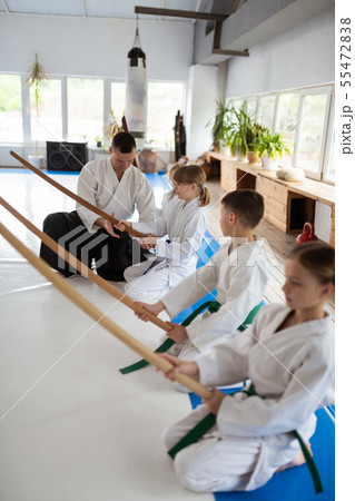 Serious children listening attentively to their aikido teacher Serious children listening attentively to their aikido teacher 55472838