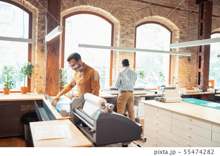 Dark-haired man standing near modern printing technique 55474282