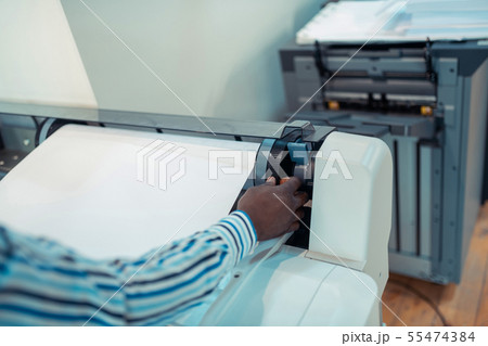 Close up of dark-skinned man using big modern printing technique 55474384