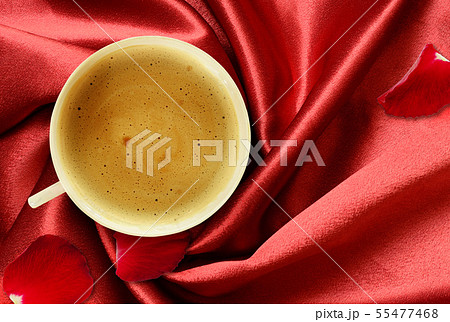 Cup of coffee and rose petals on folded red silk Cup of coffee and rose petals on folded red silk 55477468