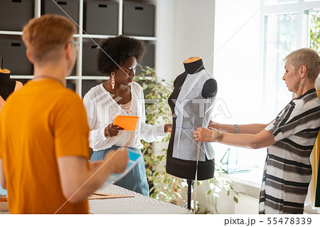 Tailor holding a tablet looking at her coworker Tailor holding a tablet looking at her coworker 55478339