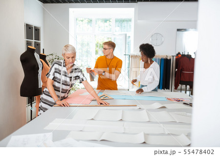 Serious aged female designer making a paper pattern 55478402