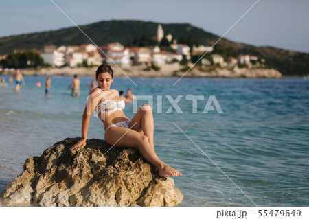 Sexy woman sit on stone in bikini. Background of little old town and sea Sexy woman sit on stone in bikini. Background of little old town and sea 55479649