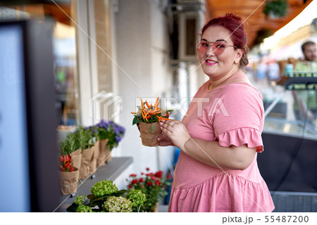 Young and fat woman holding flower pot 55487200