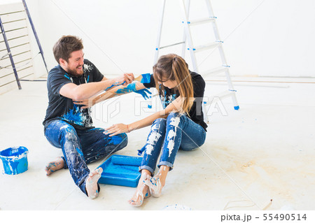 Renovation, redecoration and interiors concept - Young couple sitting on the white floor and pour 55490514