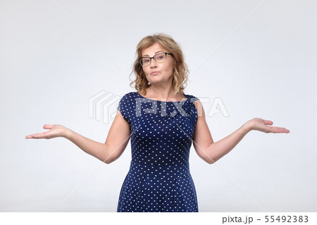 Puzzled mature female in blue dress  55492383
