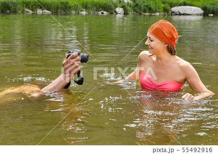 Taking pictures of smiling woman in water. 55492916