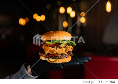 man in black gloves eating burger in the restaurant 55494988