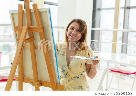 Art school, creativity and leisure concept - student girl or young woman artist with easel, palette 55500158