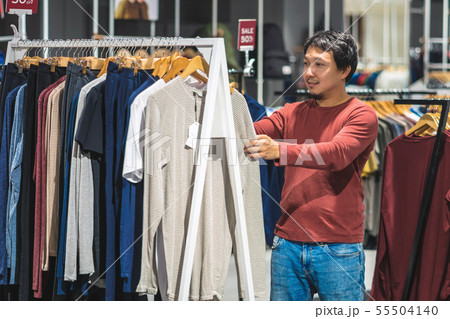 Smart asian man with beard choosing clothes in clothing store at shopping center, looking colorful t-sshirts , Fashion and Consumerism Concept. 55504140