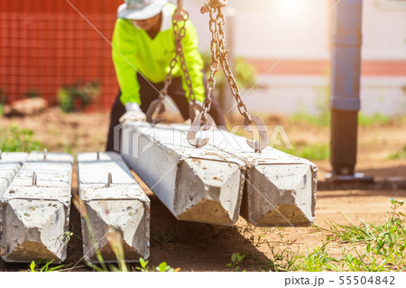 Construction worker unloading concrete stake from truck. Construction worker unloading concrete stake from truck. 55504842