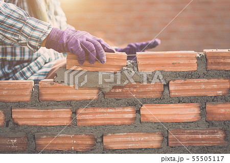 Worker installing bricks wall in process of house building 55505117