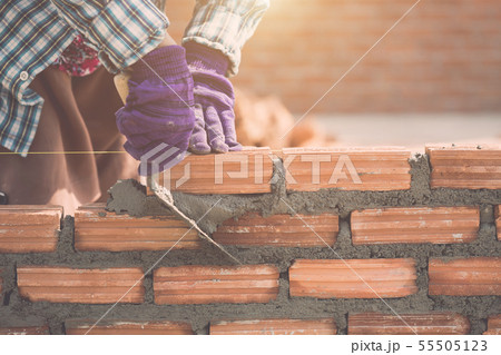 Worker installing bricks wall in process of house building Worker installing bricks wall in process of house building 55505123