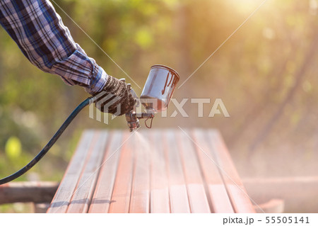 Worker spraying paint to steel pipe to prevent the rust on the surface 55505141