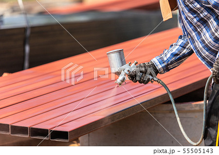 Worker spraying paint to steel pipe to prevent the rust on the surface 55505143