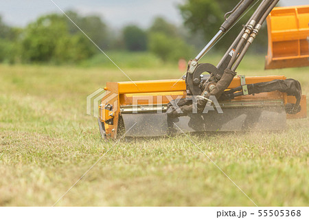 Tractor with a mechanical mower mowing grass on the side of the asphalt road. Tractor with a mechanical mower mowing grass on the side of the asphalt road. 55505368