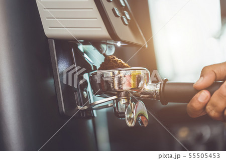 Barista making coffee grinding freshly roasted coffee beans with machine 55505453