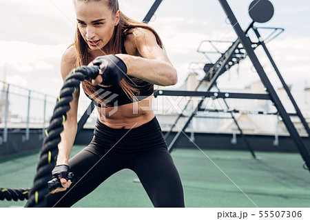 Woman doing fitness training using battle ropes Woman doing fitness training using battle ropes 55507306