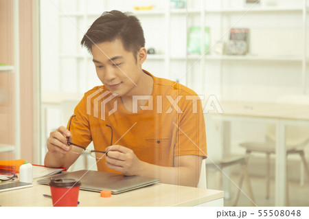 Attentive Asian male person staring at his glasses 55508048