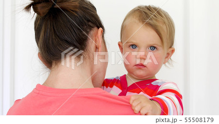 Serious child with red cheeky in hands of mother Serious child with red cheeky in hands of mother 55508179