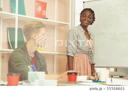 Cheerful young international teacher standing near board 55508601