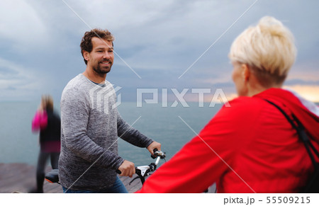 Couple with bicycles outdoors on beach, talking. Couple with bicycles outdoors on beach, talking. 55509215