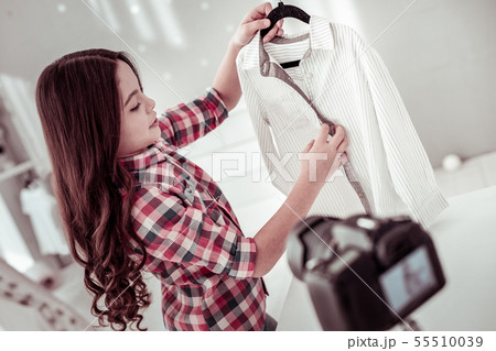 Joyful nice girl holding a hanger with her shirt Joyful nice girl holding a hanger with her shirt 55510039