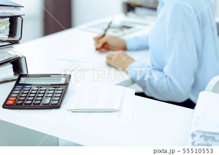 Calculator and binders with papers are waiting to be processed by business woman or bookkeeper back Calculator and binders with papers are waiting to be processed by business woman or bookkeeper back 55510553