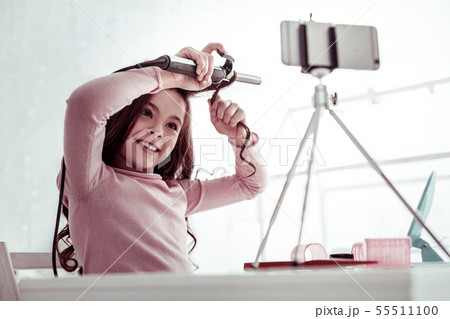 Joyful nice girl using a professional curling iron Joyful nice girl using a professional curling iron 55511100